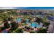 A high aerial view showcases a resort-style pool area with palm trees, a lazy river, and red umbrellas in a beautiful community at 226 Verona Ave, Davenport, FL 33897