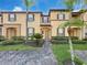Charming townhome featuring lush landscaping, a brick walkway, and decorative shutters at 226 Verona Ave, Davenport, FL 33897