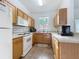 Bright kitchen featuring wooden cabinets, white appliances, and tile flooring at 226 Verona Ave, Davenport, FL 33897