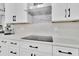 Modern kitchen features white cabinetry, black hardware, marble backsplash and countertop with integrated cooktop at 2402 Raven Croft Ct, Orlando, FL 32837