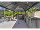 Outdoor kitchen has a built-in grill, refrigerator, sink, fan, and a dining table and chairs at 2402 Raven Croft Ct, Orlando, FL 32837
