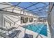 Stunning screened-in pool area featuring lounge chairs, an outdoor kitchen, and clear blue water at 2525 Shanti Dr, Kissimmee, FL 34746