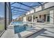 Inviting screened-in pool area featuring a spa, lounge chairs, an outdoor kitchen, and clear blue water at 2525 Shanti Dr, Kissimmee, FL 34746