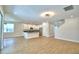 Open-concept living space with modern kitchen, dining, and living area featuring wood-look flooring throughout at 2673 Calistoga Ave, Kissimmee, FL 34741