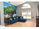 Cozy living room features a comfortable blue sofa, a large window, and a vibrant tree mural on the wall at 2807 Playing Otter Ct, Kissimmee, FL 34747