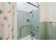 Bathroom shower with green tiling, safety grab bars, flower patterned shower curtain, and showerhead at 2830 W Oak St, Kissimmee, FL 34741
