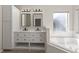 Bright bathroom featuring a double vanity with black hardware, cabinets, and a soaking tub by the window at 373 Shady Oak Loop, Davenport, FL 33896