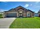 Well-maintained single-story home with a manicured lawn, dark roof, and a two-car garage at 373 Shady Oak Loop, Davenport, FL 33896