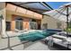Relaxing screened-in pool area features lounge chairs and an umbrella near sliding glass doors and multiple doors at 373 Shady Oak Loop, Davenport, FL 33896