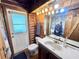 Bathroom showcasing log walls, a stylish vanity, and a unique shower curtain at 4075 Packard Ave, St Cloud, FL 34772