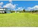 Expansive green property featuring a modern white house with black trim and large field, set against a blue sky with scattered clouds at 4075 Packard Ave, St Cloud, FL 34772
