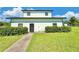 The exterior of a quaint two-story house features a concrete walkway, fresh lawn, and neatly trimmed hedges under a sunny sky at 4075 Packard Ave, St Cloud, FL 34772