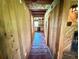 Rustic hallway with wood-paneled walls and tile flooring leading to a view of the kitchen at 4075 Packard Ave, St Cloud, FL 34772