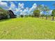 Vast green lawn with mature trees and a charming home in the distance, creating a serene landscape at 4075 Packard Ave, St Cloud, FL 34772