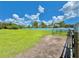 A large green backyard with a white fence, metal gate and a clear blue sky with fluffy clouds at 4125 Packard Ave, St Cloud, FL 34772