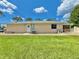 Tan single-story home featuring a well-maintained lawn and a white door, beneath a bright blue sky with scattered clouds at 4125 Packard Ave, St Cloud, FL 34772