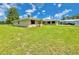 Charming single-story home with a well-manicured lawn, dark shutters, and mature trees, set against a bright blue sky at 4125 Packard Ave, St Cloud, FL 34772