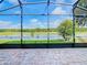 View of the lush green backyard with lake views, and a screened-in lanai at 418 Treviso Dr, Kissimmee, FL 34759