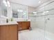 Bright bathroom featuring wood vanity, large mirror, and walk-in shower with glass surround at 418 Treviso Dr, Kissimmee, FL 34759