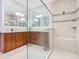 Bright bathroom featuring double sinks, wood cabinets, and modern glass shower with tiled walls at 418 Treviso Dr, Kissimmee, FL 34759