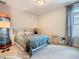 Neutral bedroom showcasing carpet, a cushioned headboard, and a large window with patterned curtains at 418 Treviso Dr, Kissimmee, FL 34759
