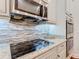 Close up on kitchen featuring stainless steel appliances, granite countertops, a cooktop, and stylish mosaic backsplash at 418 Treviso Dr, Kissimmee, FL 34759