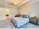Spacious main bedroom featuring a tray ceiling, a statement chandelier, and access to the ensuite bathroom at 418 Treviso Dr, Kissimmee, FL 34759