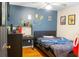 A bedroom featuring a desk, blue accent wall, and a modern black bedframe with blue accents at 423 Midway Ave, Mascotte, FL 34753
