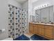 Well-lit bathroom with double sinks, beach themed shower curtain and blue rugs at 504 Terrace Ridge # 311, Davenport, FL 33896