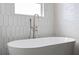White tub and modern fixtures create a luxurious bathing experience, complemented by white tiled walls at 6905 Beargrass Rd, Harmony, FL 34773