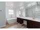 Bathroom featuring a soaking tub, dual sinks, and white tiled walls creating a spa-like retreat at 6905 Beargrass Rd, Harmony, FL 34773