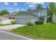 Charming home exterior featuring a two-car garage, lush green lawn, and mature landscaping at 6905 Beargrass Rd, Harmony, FL 34773