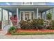 Inviting front porch with stylish columns, vibrant plants and a red front door at 6905 Beargrass Rd, Harmony, FL 34773