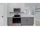 Modern kitchen with stainless steel appliances and gray and white cabinetry at 6905 Beargrass Rd, Harmony, FL 34773
