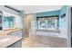 Bright bathroom featuring a soaking tub, glass shower, double vanity, and a large window with backyard views at 716 Timberwilde Ave, Winter Springs, FL 32708