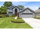 Inviting two-story home with a lush green lawn, mature landscaping, and an attached two-car garage at 716 Timberwilde Ave, Winter Springs, FL 32708