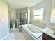 Bathroom featuring a soaking tub, frameless shower, and a window, finished with modern tile at 841 Fir Ave, Frostproof, FL 33843