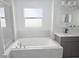Bright bathroom featuring a soaking tub, gray tile surround and chrome fixtures at 841 Fir Ave, Frostproof, FL 33843