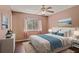 Stylized main bedroom with a large window, light walls, a ceiling fan, hardwood floors, and coastal decor at 8733 Catbriar Ln, Orlando, FL 32829