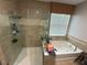 Bathroom featuring a glass shower, soaking tub, and beige tile at 8986 Fullerwood Ave, Orlando, FL 32832