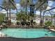 Screened-in pool with waterfall feature, surrounded by lush landscaping and swaying palm trees at 8986 Fullerwood Ave, Orlando, FL 32832