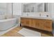 A modern bathroom featuring a soaking tub, double vanity with a wooden cabinet, and wood-look flooring at 933 Jasmine St, Celebration, FL 34747