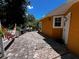 View of brick paver patio surrounded by garden features and an orange colored exterior of the home at 10207 Cody Ln, Orlando, FL 32825