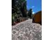 Paver patio runs along the side of the orange house with mulch beds, a white picket fence, and mature trees at 10207 Cody Ln, Orlando, FL 32825