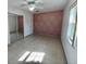 A bright bedroom features a diamond patterned accent wall, closet, and neutral tile flooring at 1211 Lehigh St, Kissimmee, FL 34744
