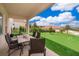 Covered patio area with an outdoor dining set overlooking the beautifully landscaped backyard at 1776 Bella Lago Dr, Clermont, FL 34711