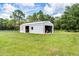A large, white barn with open and closed doors, set within a lush green landscape at 1781 Terra Verde Ln, Chuluota, FL 32766