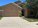 Two-story home with a two-car garage, tan exterior, and a well-manicured front yard with a large tree at 2106 Congress Ln, St Cloud, FL 34769