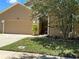 Two-story tan home with a tree-lined lawn, front entrance, and two-car garage providing great curb appeal at 2106 Congress Ln, St Cloud, FL 34769