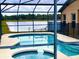 Screened-in pool and spa overlooking a tranquil lake, complete with a lounge chair for relaxation at 2281 Royal Ridge Dr, Davenport, FL 33896